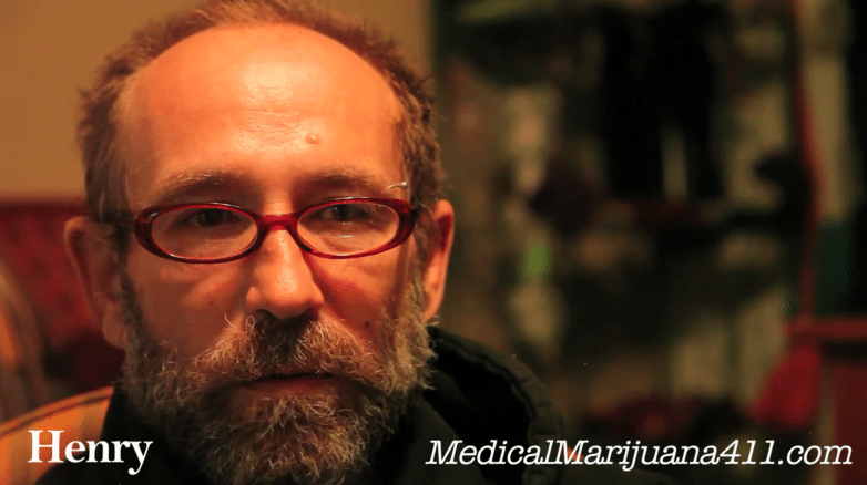 Bearded man in red glasses in a video interview, captioned Henry, MedicalMarijuana411.com