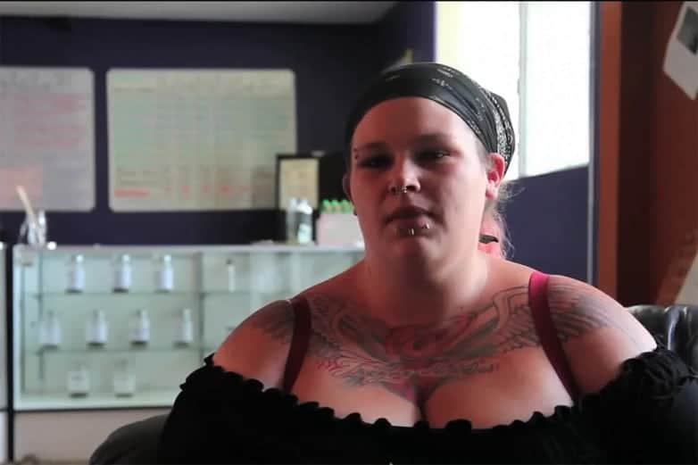 Woman with a bandana, nose ring and chest tattoos seated during an interview