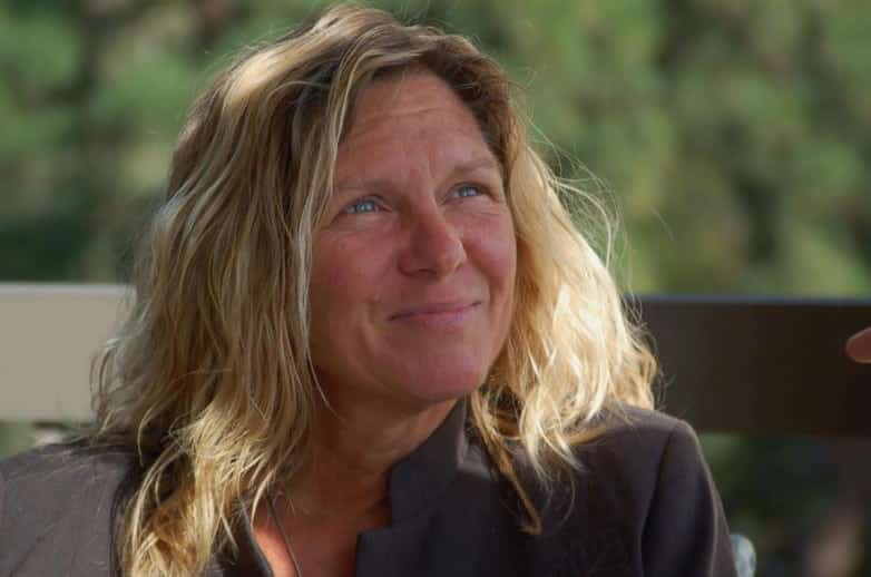 Blonde woman with wavy hair smiling during an outdoor interview
