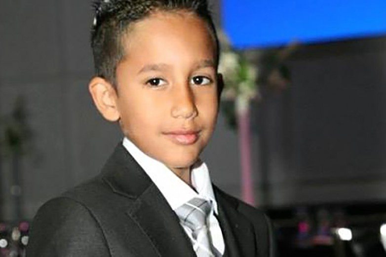 Young boy in a dark suit and silver tie at a formal event