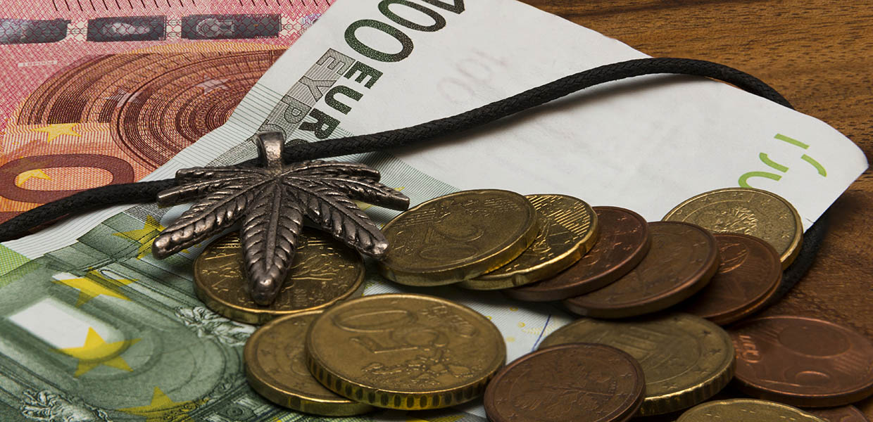 Cannabis leaf with coins and euro banknotes on a wooden table